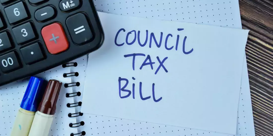 'Council tax bill' on a piece of paper on an open dotted notebook, with a calculator and pens