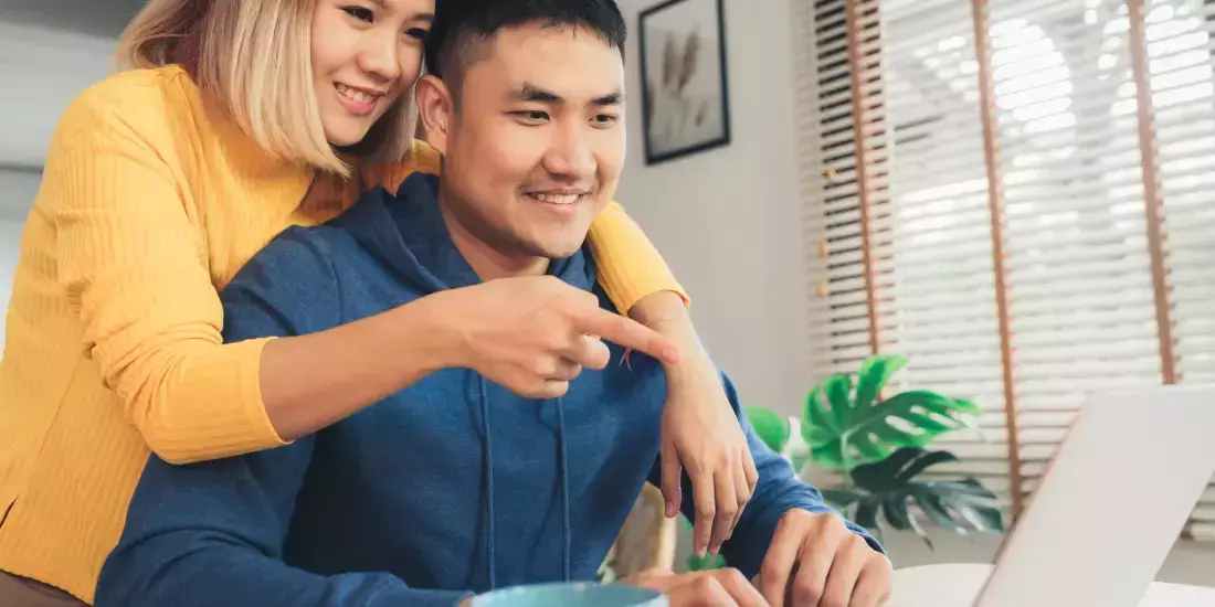 An Asian couple look at a computer screen together