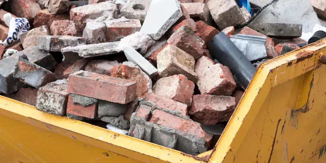 A yellow skip full of bricks and rubble