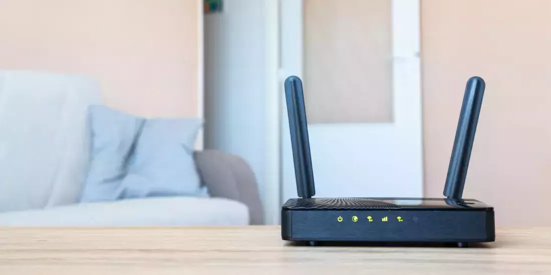 A broadband router on a tabletop in focus with an open doorway out of focus behind